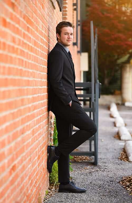 high school senior boy posing against a wall